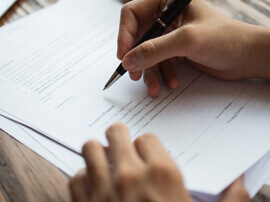 Close up of hand holding a pen to sign a form.