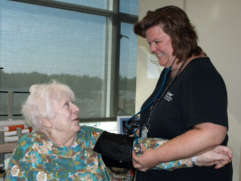 Nurse checking senior female patients vitals using blood pressure cuff