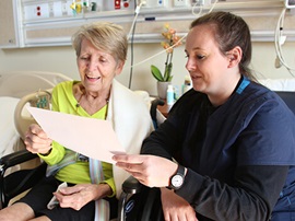 Female therapists and female patient in wheelchair looking at a paper form.