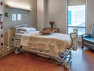 Hospital room with a bed, table and chair.