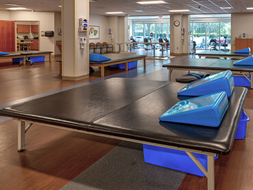 A king-sized therapy table with blue headrests in a therapy gym.