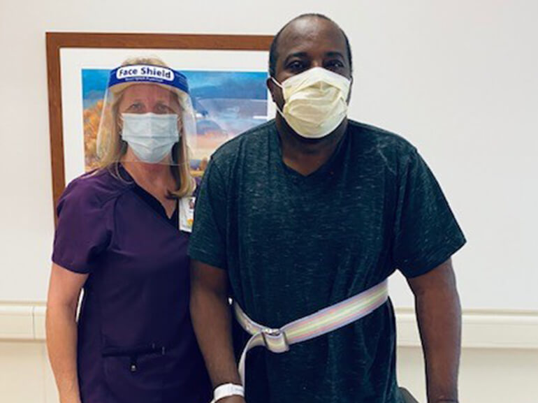 Vance wearing hospital mask and standing next to a female therapist in a hallway.