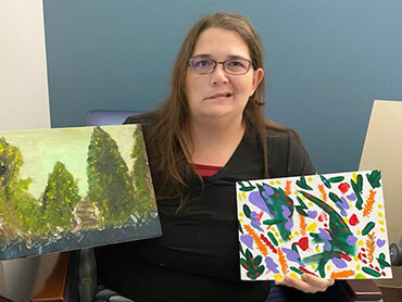 Tasha holding two of her paintings done in art therapy classes.