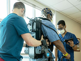two physical therapists assisting a patient while he is walking